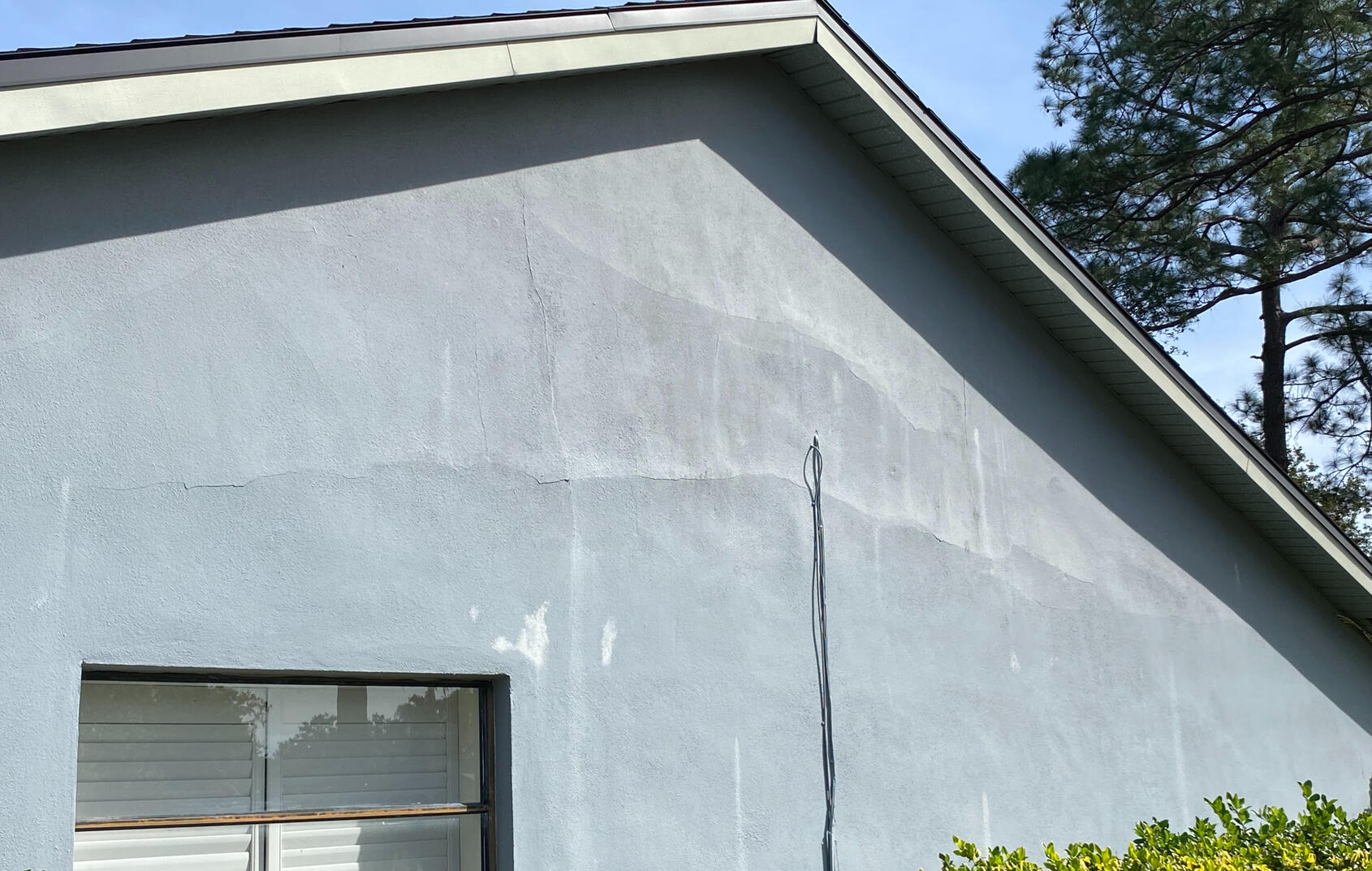 Large cracks in stucco show signs of extensive water intrusion.