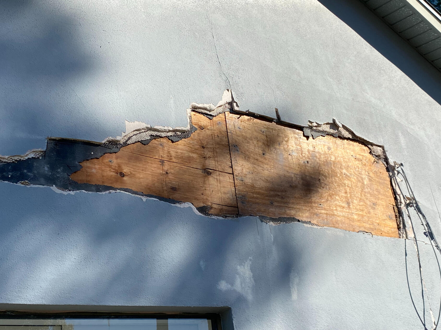 Large cracks in stucco show signs of extensive water intrusion.