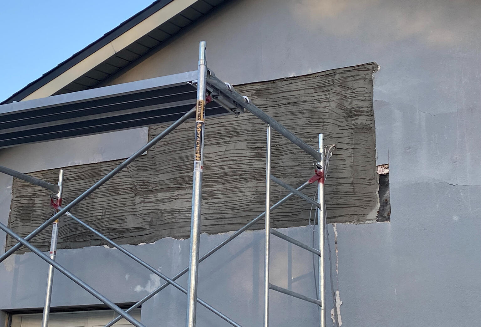 Large cracks in stucco show signs of extensive water intrusion.